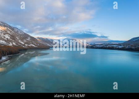 Luftaufnahme der Winterlandschaft von See und Wald in Kanas, bei Sonnenaufgang. Stockfoto