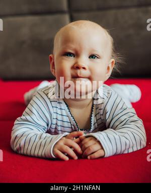 Neugierig Baby Mädchen liegt auf dem Bett und lächelte, Vorderansicht Stockfoto