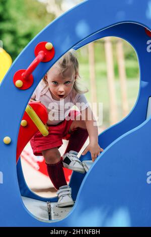 Junge blonde Mädchen haben Spaß auf Kinderspielplatz Stockfoto