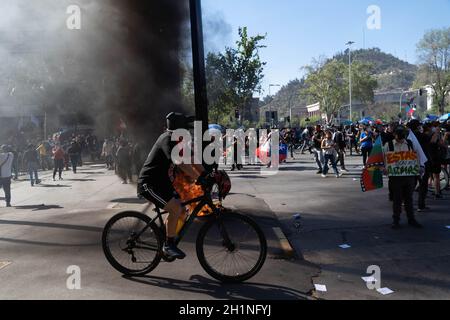 Santiago, Metropolitana, Chile. Oktober 2021. Ein Protestler auf dem Fahrrad passiert eine Barrikade während eines Protestes zum zweiten Jahrestag des sozialen Ausbruchs gegen die Regierung Sebastian Pinera am 18. Oktober 2021 in Santiago, Chile. (Bild: © Matias Basualdo/ZUMA Press Wire) Stockfoto