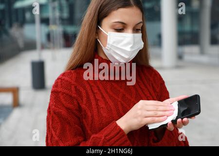 Portrait der Frau mit Schutzmaske Desinfektion Reinigung Handy Touchscreen verhindert das Abwischen gegen Kontamination Stockfoto