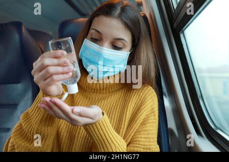 Fahren Sie sicher mit öffentlichen Verkehrsmitteln. Junge Frau mit OP-Maske mit Hand Desinfektionsmittel Gel aus Spender. Pendler mit Schutzmaske desinfiziert ha Stockfoto