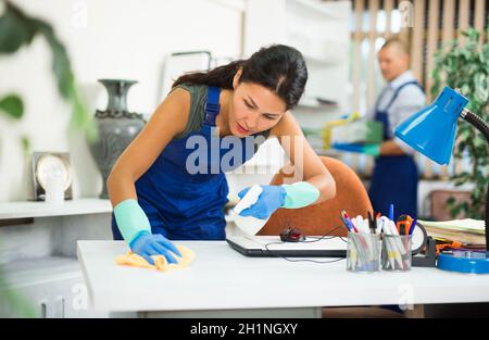 Arbeitsfrau der Reinigung Service wischen Staub auf Möbeln im Büro Stockfoto