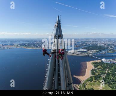 Arbeiter Installateure in der Höhe arbeiten an der Spitze des Wolkenkratzers. Stockfoto