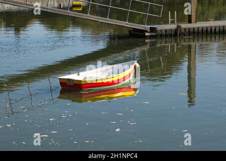 Kleines Boot mit bunten Streifen, das am Dell Quay in Chichester Harbour, West Sussex, England, festgemacht ist Stockfoto