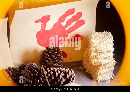 Rote Hand pute auf Vanille-Baupapier mit Heu und Kiefernzapfen, in gelbem Rahmen Stockfoto