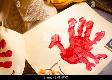 Rote Hand pute auf Vanille-Baupapier mit orangen Beeren Und fallen Laub auf sie und burlap im Hintergrund Stockfoto