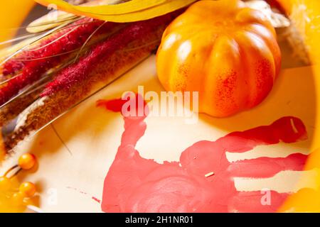 Rote Hand-pute auf Vanille-Baupapier mit einem kleinen orangen Kürbis, und braunem und rotem Laub Stockfoto