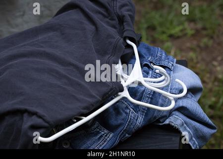 Nahaufnahme von blauen Jeans und T-Shirts auf weißen Kleiderbügeln Stockfoto