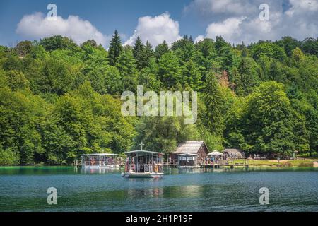 Plitvicka Jezera, Kroatien, Juli 2019 Fähre mit Touristen Abfahrt kleinen Hafen, um den See zu überqueren. Nationalpark Plitvicer Seen UNESCO Weltkulturerbe Stockfoto
