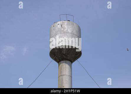 Silber Wasserturm unter grünem Rasen und Bäumen. Stockfoto