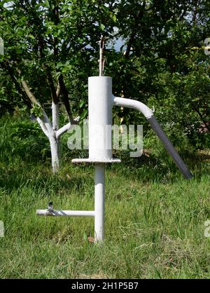 Handpumpe führt zu einem artesischen Brunnen. Pumpen von Wasser für die Bewässerung des Gartens. Stockfoto