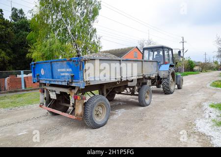 Krasnodar, Russland - 19. April 2018: Ein Traktor mit einem Schutthotterwagen für die Reparatur der Straße. Fütterungslöcher auf der Straße. Straßenreparatur. Stockfoto