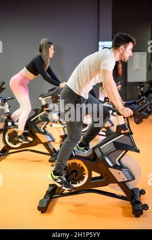 Mann, der auf einem modernen Fitness-Fahrrad während der Gruppe Spinning-Klasse in der Turnhalle. Hochwertige Fotos Stockfoto
