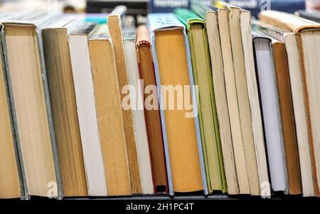 Reihe von vielen alten gebrauchten Büchern, die in der örtlichen Antiquariatsbuchhandlung ausgestellt sind, Foto mit geringer Schärfentiefe, nur wenige Seiten im Fokus. Stockfoto