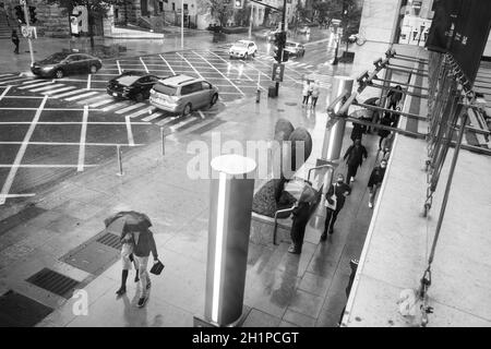 Fußgänger flanieren an einem regnerischen Tag auf der Sherbrooke Street in Montreal, Quebec, Kanada, in der Nähe des Montreal Museum of Fine Arts Stockfoto