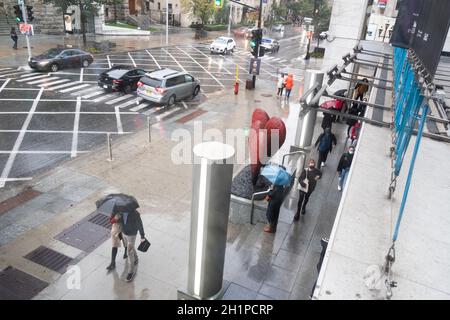 Fußgänger flanieren an einem regnerischen Tag auf der Sherbrooke Street in Montreal, Quebec, Kanada, in der Nähe des Montreal Museum of Fine Arts Stockfoto