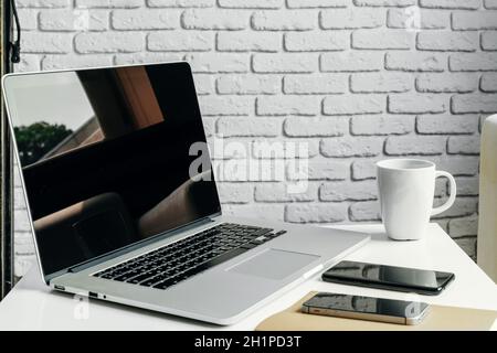 Öffnen Sie Ihren Laptop auf dem Tisch in der Nähe des Sofas, und wohnen Sie im Inneren. Konzept des freien Arbeitsplatzes Stockfoto