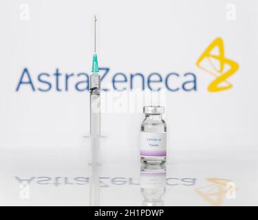 Teo, Spanien; 25. Januar 2021: Impfkonzept AstraZeneca Covid-19. Eine Spritze und ein Fläschchen über dem Firmenlogo von AstraZeneca verschwommen im Hintergrund. Stockfoto