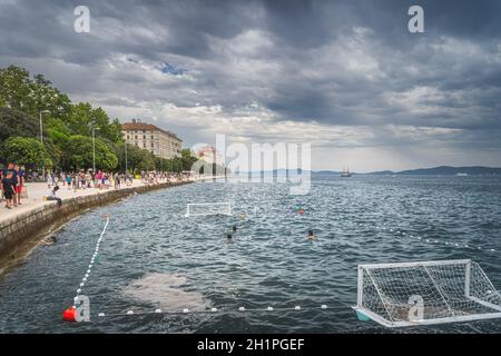 Zadar, Kroatien, Juli 2019 Massen von Touristen zu Fuß und entspannen an der Küste von König Petar Kresimir IV. Menschen spielen Wasserball in der Adria Stockfoto