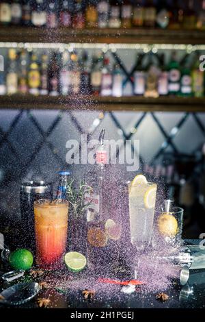 Mehrere alkoholische Cocktails an der Bar in verschiedenen Gläsern. Cocktaildekoration: Limette, Minze, Orange, Sirup. Stockfoto