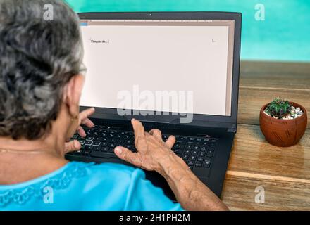 Ältere Frau tippen auf einem Laptop Dinge zu tun Stockfoto