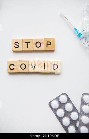 Stoppen Sie die Inschrift des Coronavirus. Vorbereitung für die Impfung gegen covid-19. Spritze, Impfstoff, Pillen, medizinische Maske Stockfoto