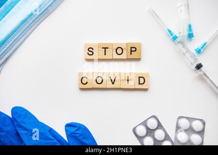 Stoppen Sie die Inschrift des Coronavirus. Vorbereitung für die Impfung gegen covid-19. Spritze, Impfstoff, Tabletten, medizinische Maske, Handschuhe Stockfoto