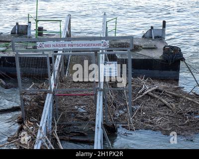 Schwimmende Anlegestelle mit Flotsam und Inschrift „bei Nässe Rutschgefahr“ am Hochwasser des Rhein - Köln Stockfoto