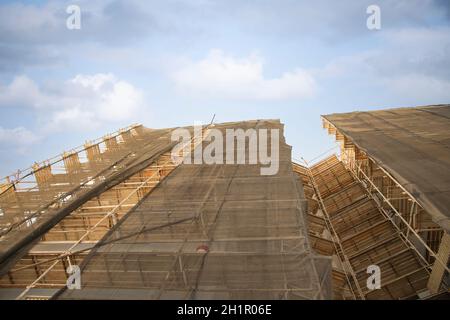 Baustelle mit einem Schutznetz an der Fassade eines Gebäudes mit Gerüsten. Altes Wohnhausrenovierungskonzept. Konzept von Erfolg, Wachstum, Richtung. Ein Pfeil markiert den Pfad. Hochwertige Fotos Stockfoto