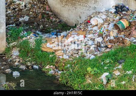 Abfall Abfall an der Seite eines Flusses unter einer Brücke Stockfoto