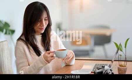 Attraktive junge Frau genießt ihren Morgenkaffee in einem Café Co-Working-Space. Entspannen Sie sich vor der Arbeit Stockfoto