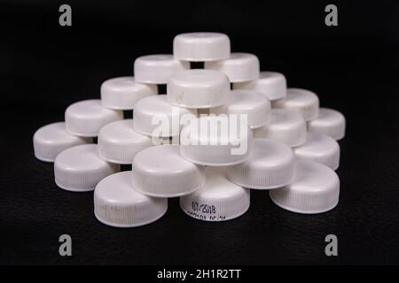 Eine organisierte Gruppe von gebrauchten Kappen aus Kunststoff Flaschen auf eine schwarze Fläche Stockfoto