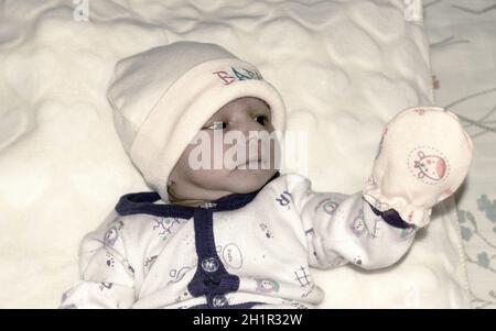 Nahaufnahme Portrait Bild von niedlichen schönen liebenswert Baby junge asiatische und indische Ethnizität in Winterkleidung liegen des Bettes auf weißer Decke. Einen Monat alt Stockfoto