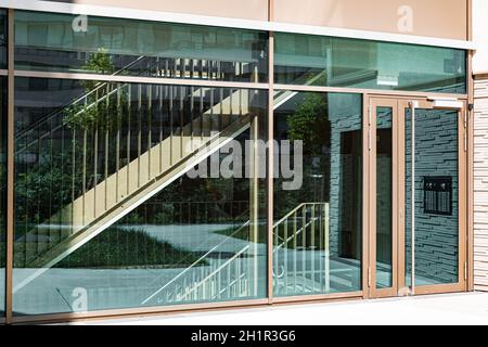 Eingang mit transparenten Fenstern und Tür, durch die transparente Tür können Sie die Treppe sehen, sonnigen Tag Stockfoto