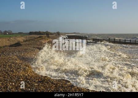 Stürmisches Wetter mit Wellen am Kiesstrand bei Climping in der Nähe von Littlehampton, West Sussex, England. Sturmschäden an der Küstenabwehr. Stockfoto