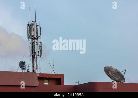 Elektronische Kommunikation und Mobiltelefon ragen unter teilweise bewölktem Himmel auf Stockfoto