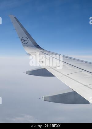 Linker Flügel eines Airbus A320 von Lufthansa German Airlines auf 200 Flugnummer LH900 von Frankfurt nach London, gegen einen Blauen Himmel und einen Weißen Wolken-Cov Stockfoto