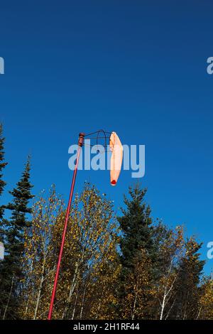 Ein Windsack hängt ruhig an einem blauen Himmel. Stockfoto