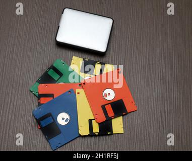 Alte bunte Retro-Disketten und moderne externe Festplatte Auf Holztisch Stockfoto