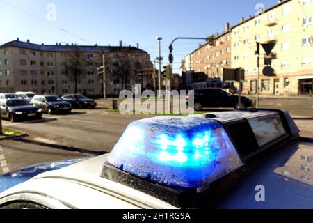 Blaues Blinklicht auf einem Polizeiauto in einer Stadt in Deutschland. Häuser, Autos und Straßen im Hintergrund. Stockfoto
