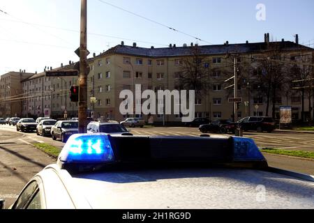 Blaues Blinklicht auf einem Polizeiauto in einer Stadt in Deutschland. Häuser, Autos und Straßen im Hintergrund. Stockfoto