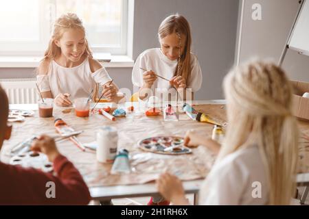 Glückliche Kinder malen in der Schule mit bunten Farben auf Papier Stockfoto