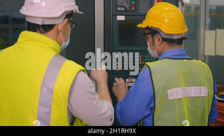 Asiatische Fabrik Arbeiter Mann Betrieb automatisierte Programmierung CNC-Frässteuerung Maschinenindustriezentrum in Werkzeugwerkstatt Fertigung mit Ingenieur Mann Stockfoto