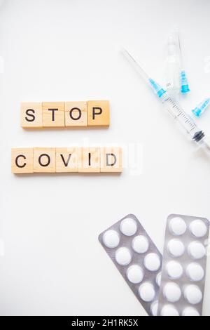 Stoppen Sie die Inschrift des Coronavirus. Vorbereitung für die Impfung gegen covid-19. Spritze, Impfstoff, Pillen, medizinische Maske Stockfoto