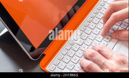 Männliche Hände und weiß orange Convertible Notebook Stockfoto