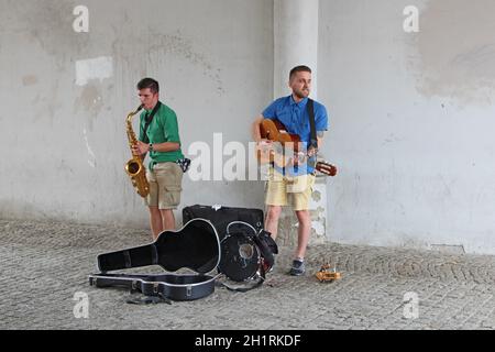 Straßenmusiker spielen Gitarre und Saxophon. Musiker spielen draußen in Danzig. Gitarrist und Saxophonist verdienen ihren Lebensunterhalt mit dem Spielen. Junger Musiker Stockfoto