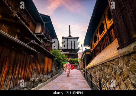 Japanisches Mädchen in Yukata mit rotem Regenschirm in der Altstadt von Kyoto, Japan Stockfoto