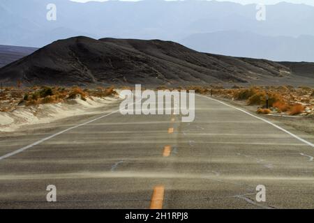 Sand weht über die Straße in der Nähe von Stovepipe Wells, Death Valley Nationalpark, Mojave-Wüste, Kalifornien, USA Stockfoto