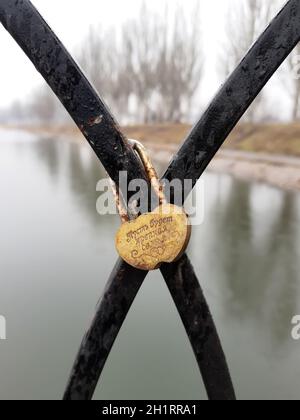 Gelbe Burg in Form eines Herzens auf einem schwarzen Metallzaun des Stadtdamms. Metallvorhängeschloss. Möge es eine starke Familie geben. Stockfoto